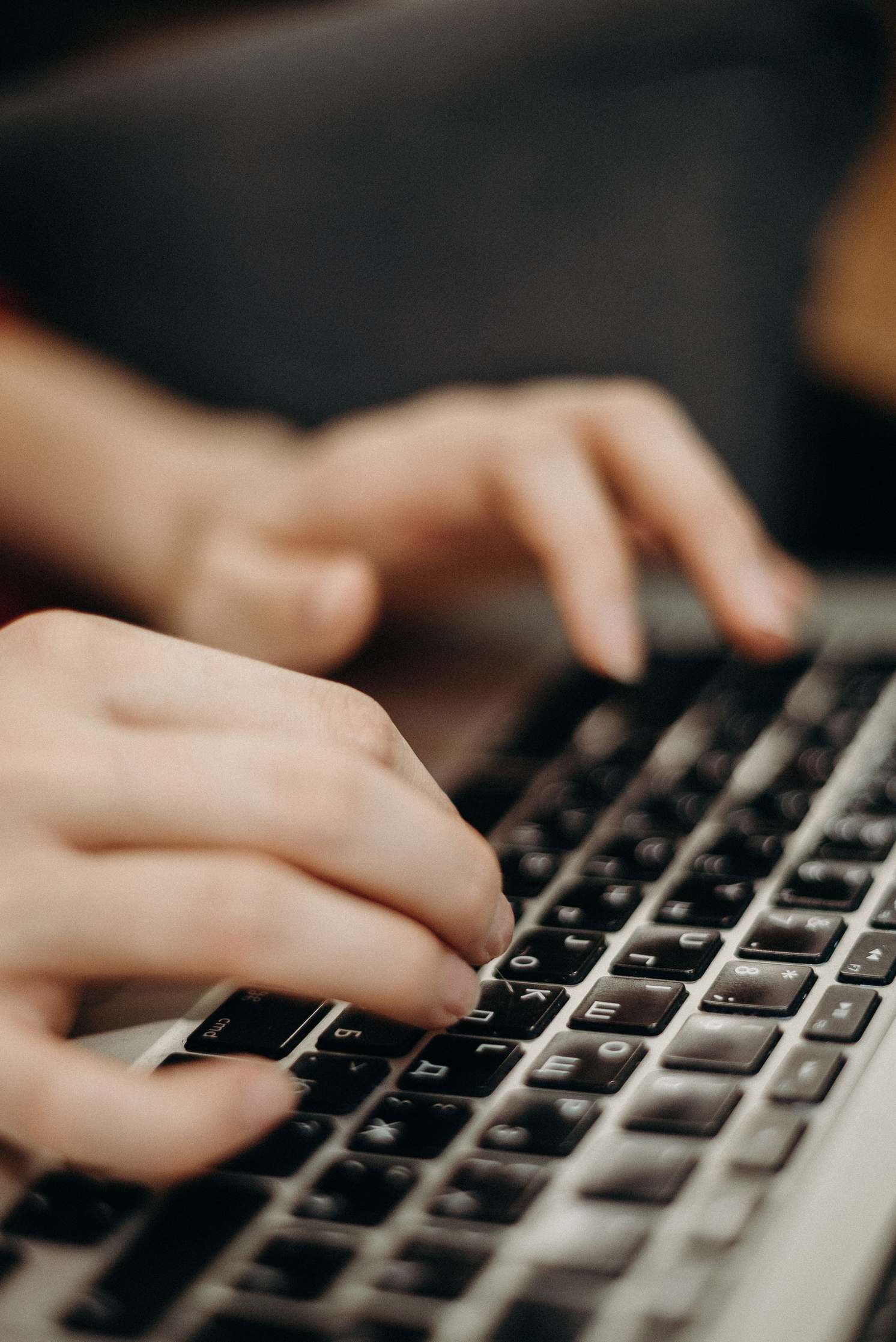 Hände an der Tastatur neben einem Laptop
